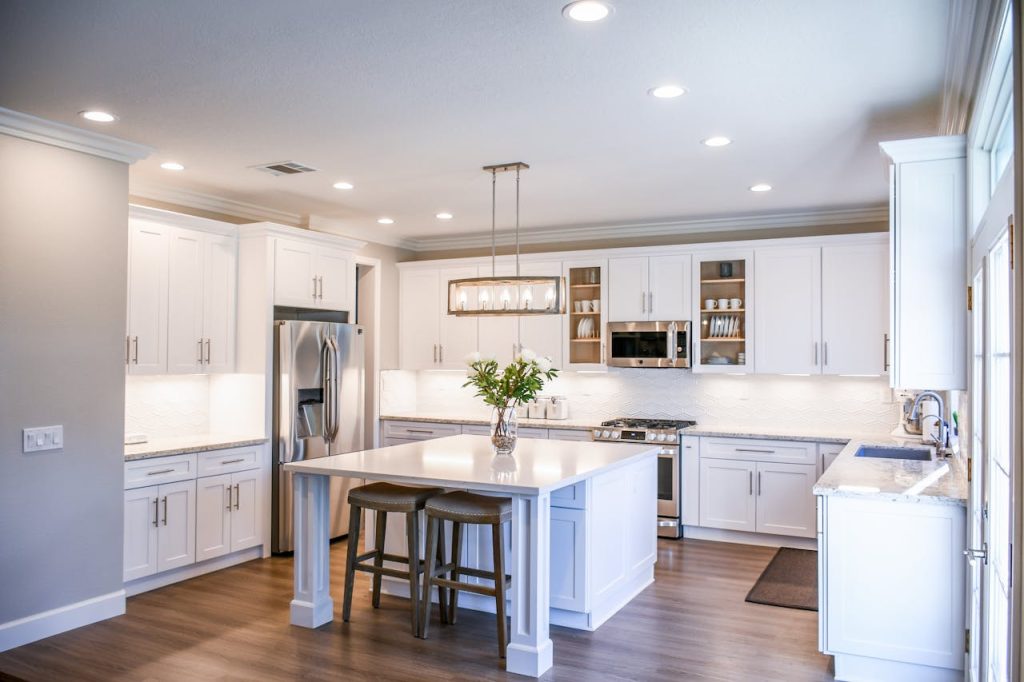 kitchen-with-furniture-and-appliances-2724748 Elegant white kitchen featuring an island, modern appliances, and ample natural light.
