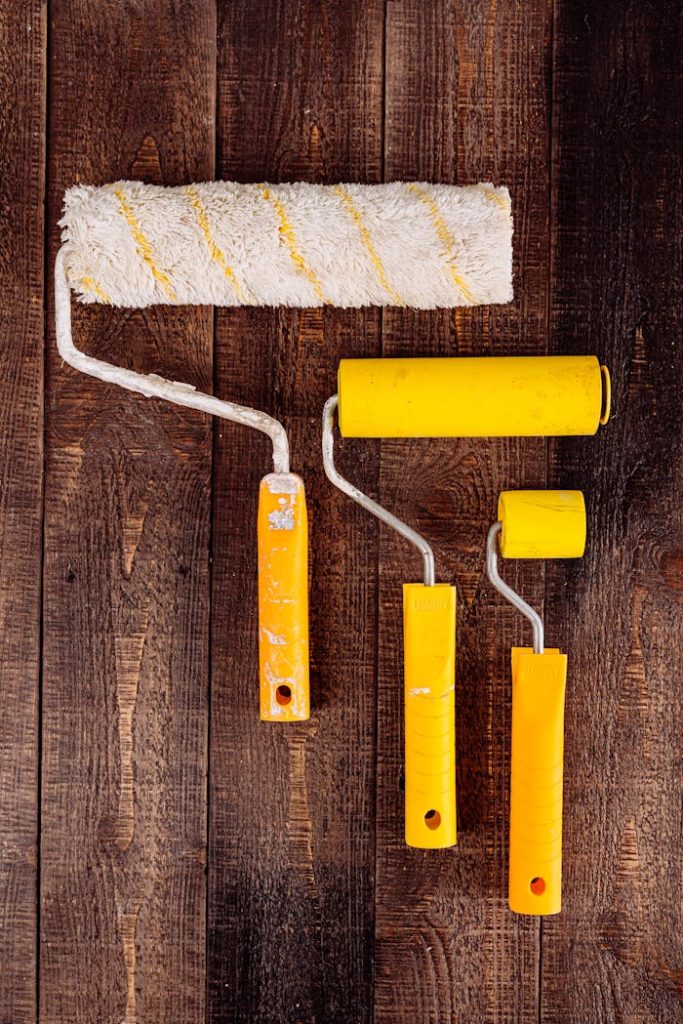 paint-rollers-on-wooden-table-5853925 Top view of yellow paint rollers arranged on a wooden table for DIY projects.