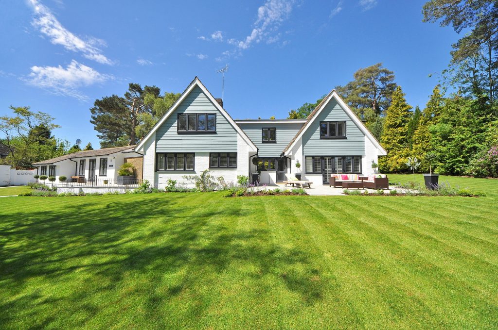 pexels-photo-280222-280222 Modern family home exterior showcasing a large lawn and garden under a clear blue sky.