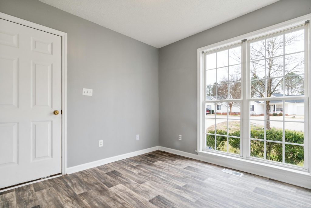 pexels-photo-7028101-7028101 Bright and spacious empty room with wooden flooring and large window, perfect for residential property listings.